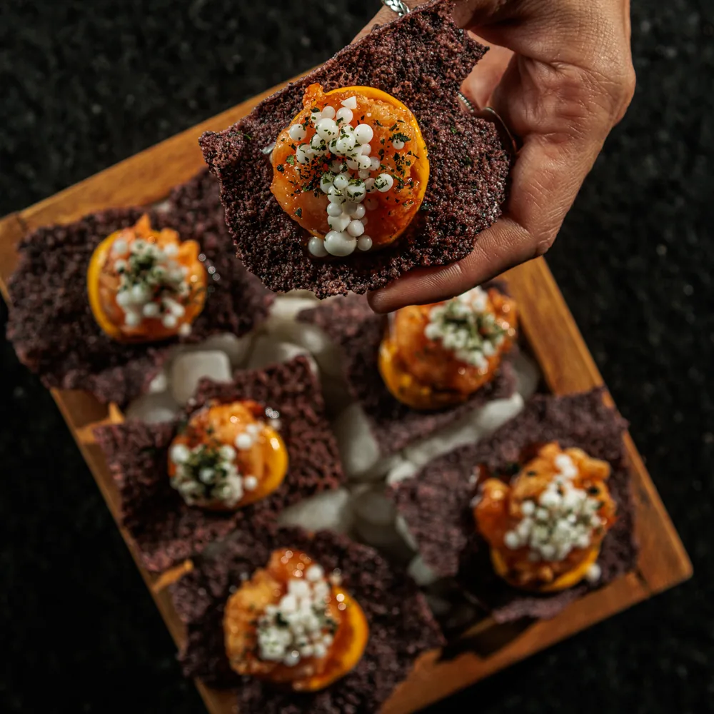 Entrada servida sobre cracker de arroz negro, no Voar